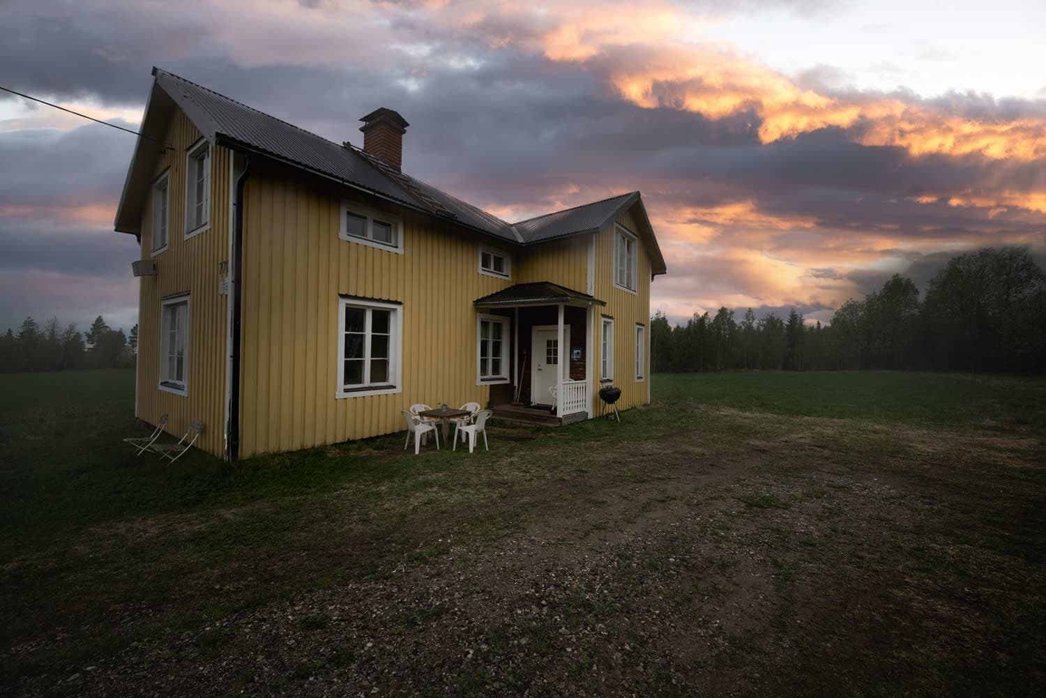 Yellow farmhouse at sunset on open field, rural scenic stay