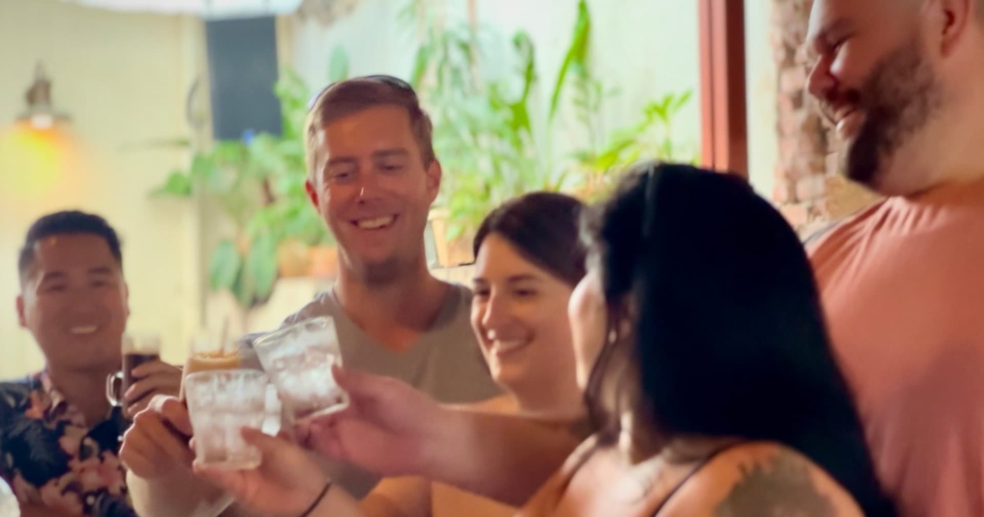 Friends toasting drinks inside a cozy bar during island tour