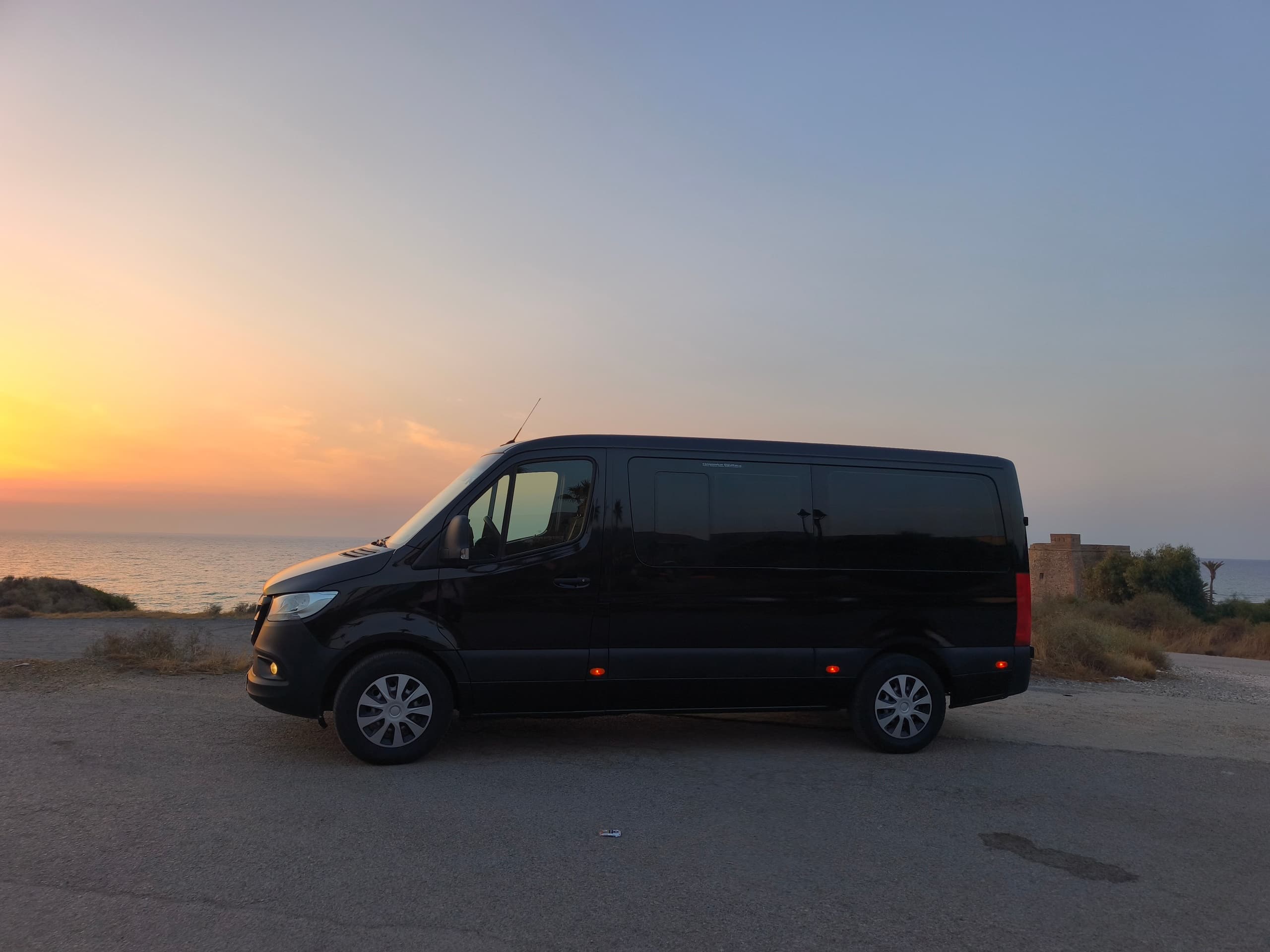 Two vans parked by harbor with skyline and water views