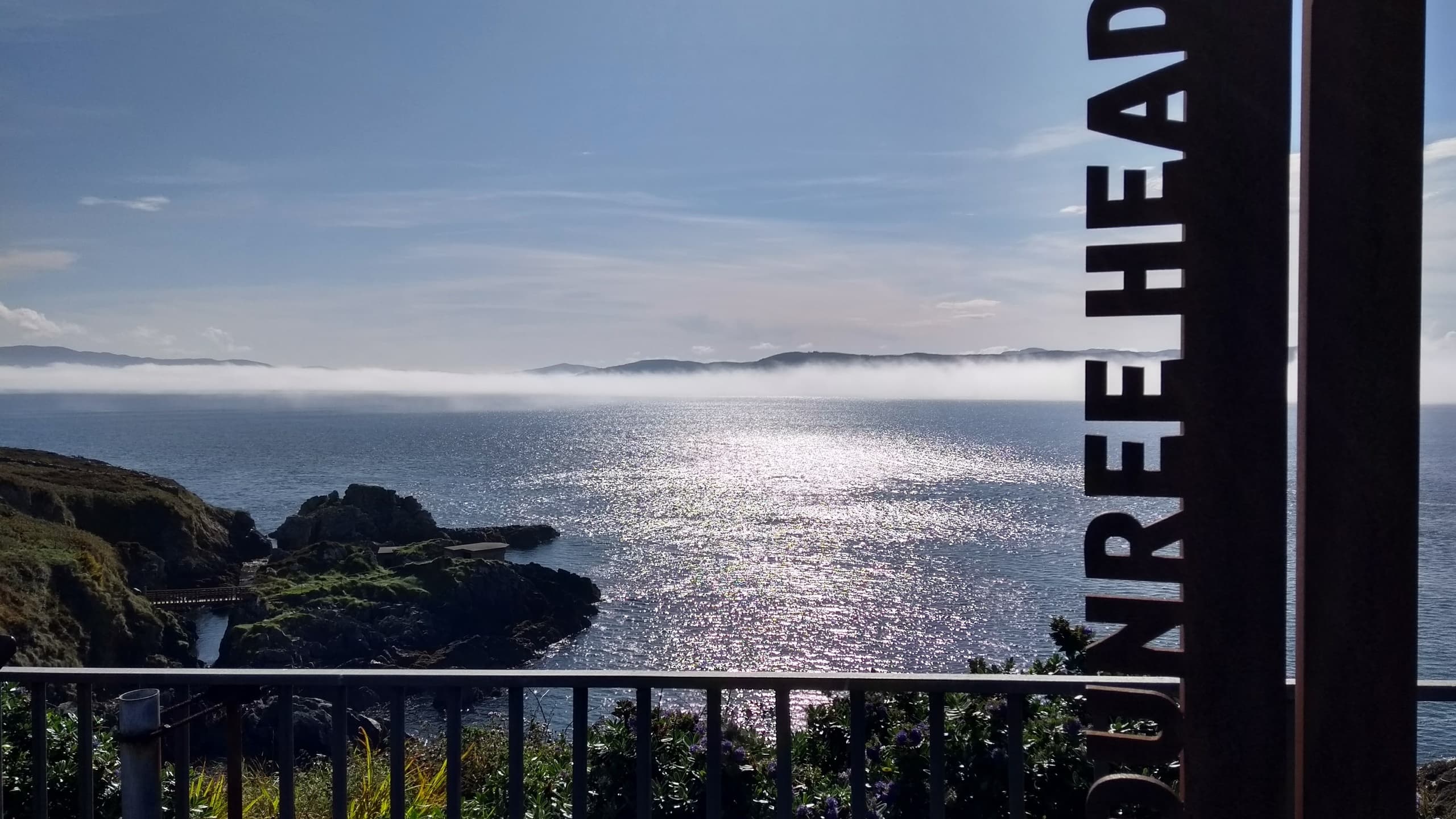 Coastal headland lookout over sunlit Atlantic sea, scenic vista