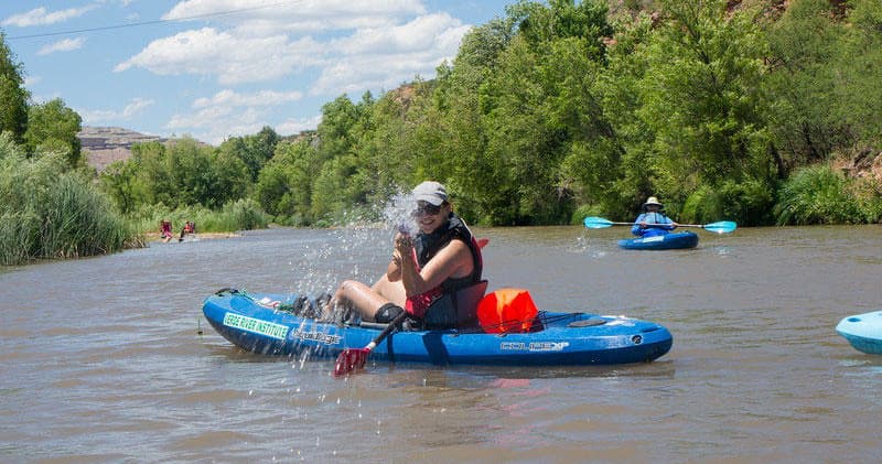 Solo kayaker splashing paddles on a scenic slow river trip