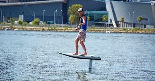 E-foil rider gliding above harbor waters near coastal city