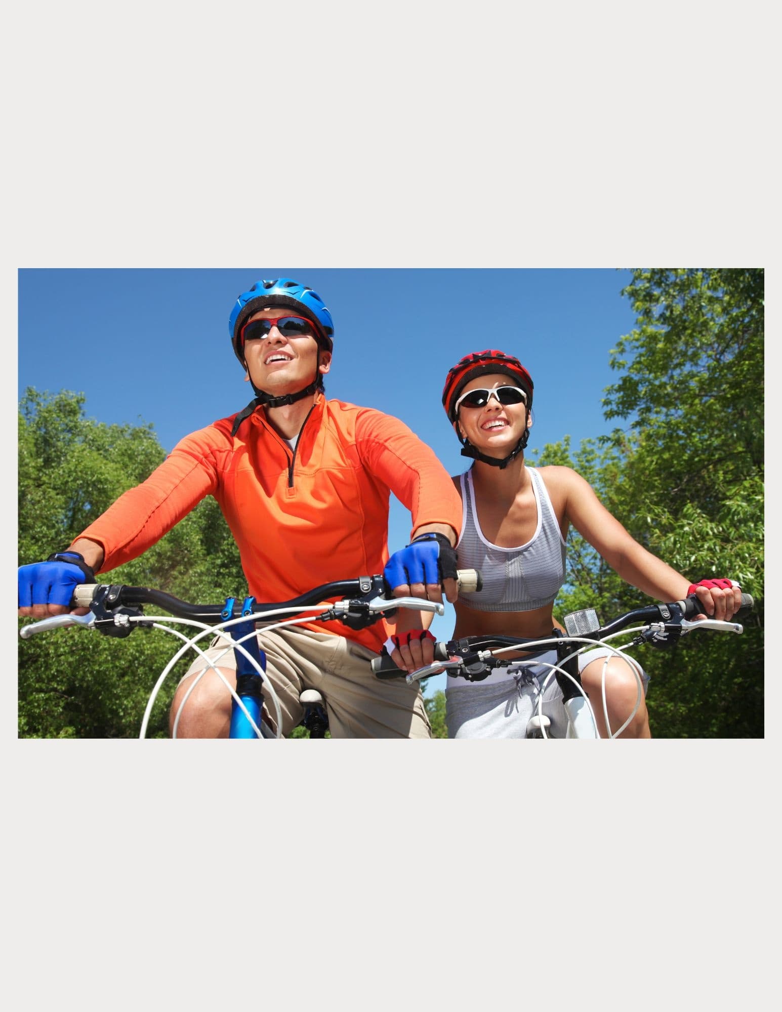 Couple cycling electric bikes smiling on sunny green trail