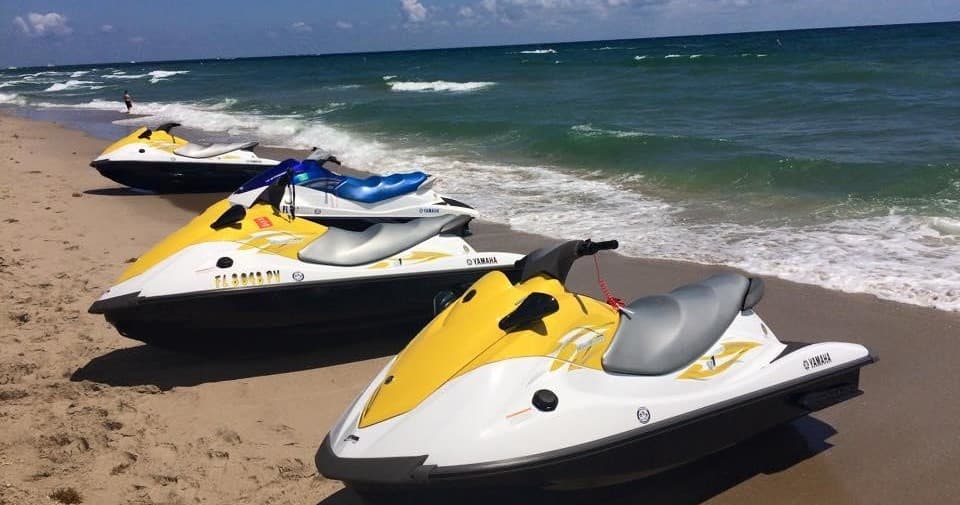Yellow jet skis lined on sandy beach with ocean waves
