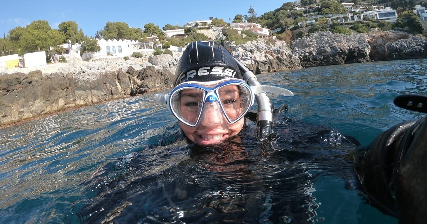 Diver at surface smiling with coastal village backdrop, ocean