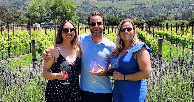 Three friends enjoying wine tasting in a vineyard