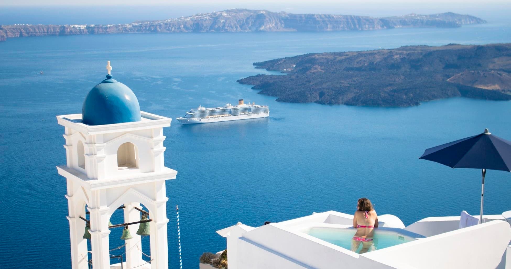 Blue-domed church and cruise ship in Santorini caldera view