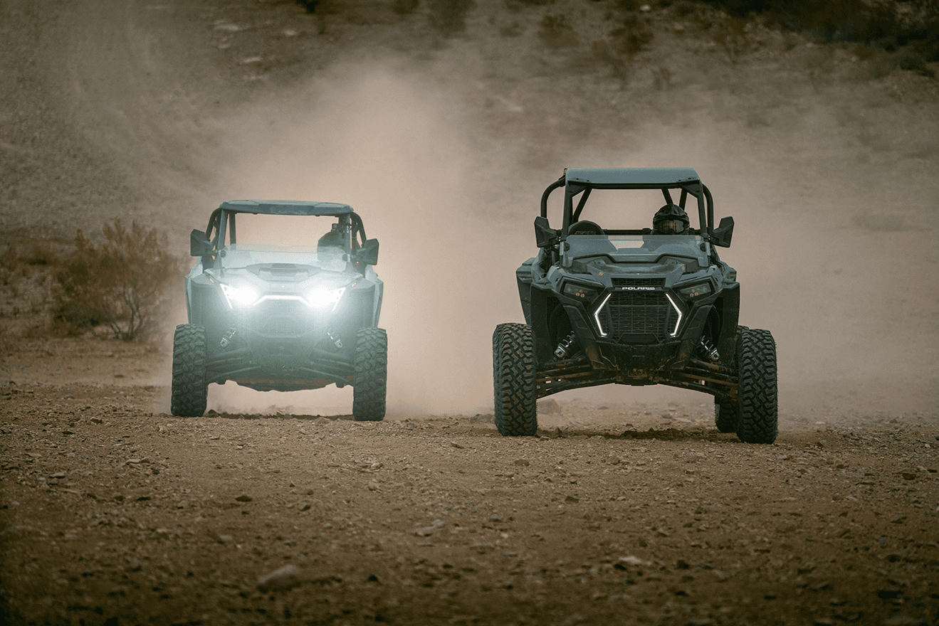 Two off-road UTVs kicking up dust on a desert trail ride