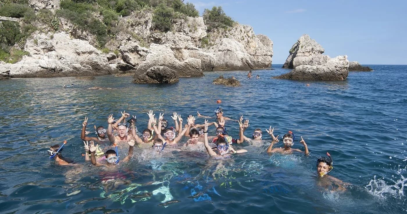 Large group swimming and celebrating in rocky coastal cove