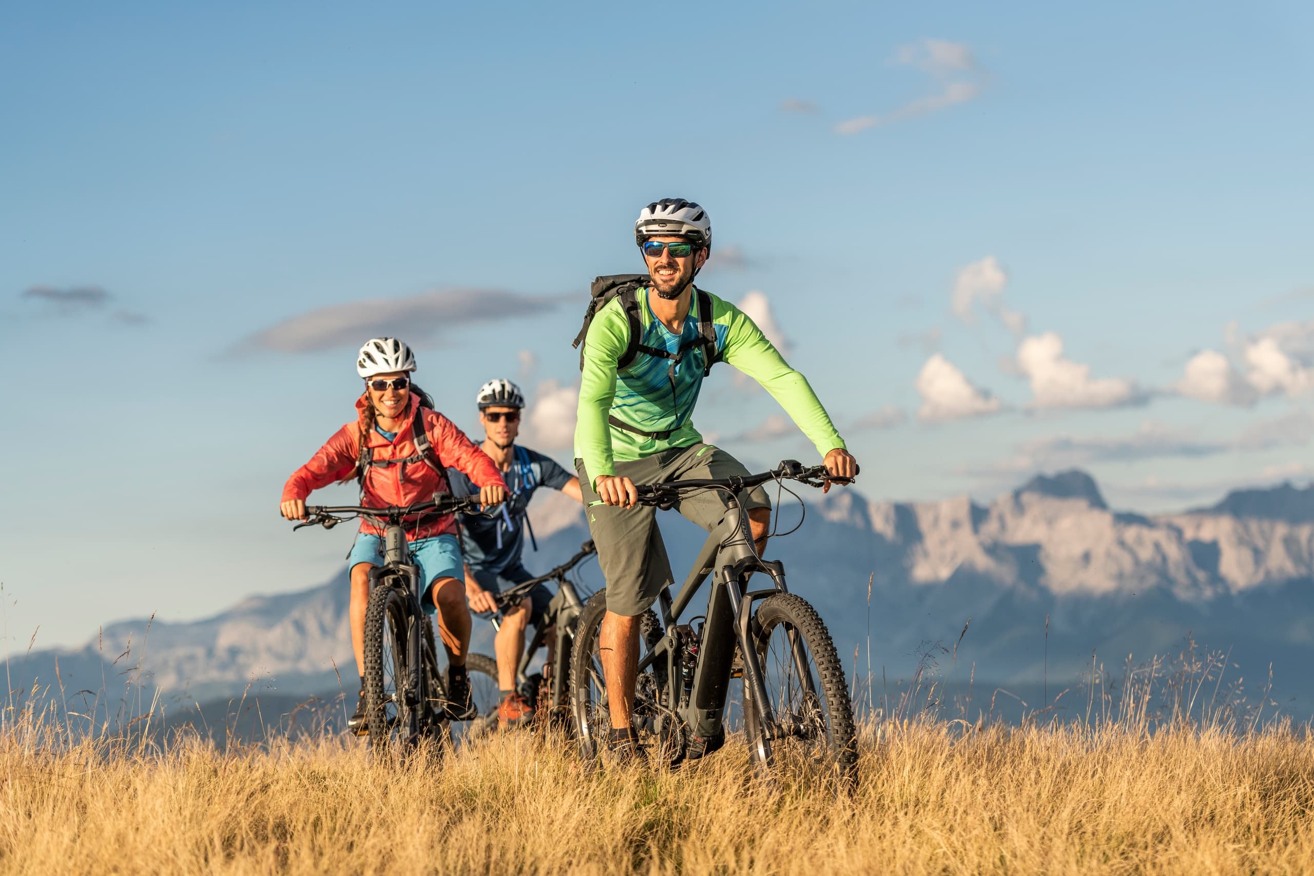 Mountain bikers riding alpine trail with rugged valley views
