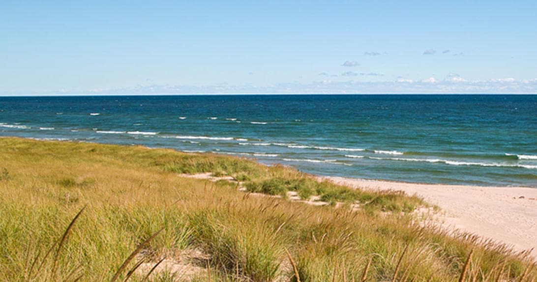 Sandy dunes and Lake Michigan shoreline on clear summer day