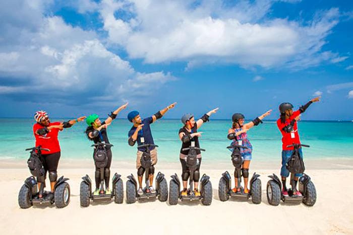 Segway tour group on white-sand beach under blue sky