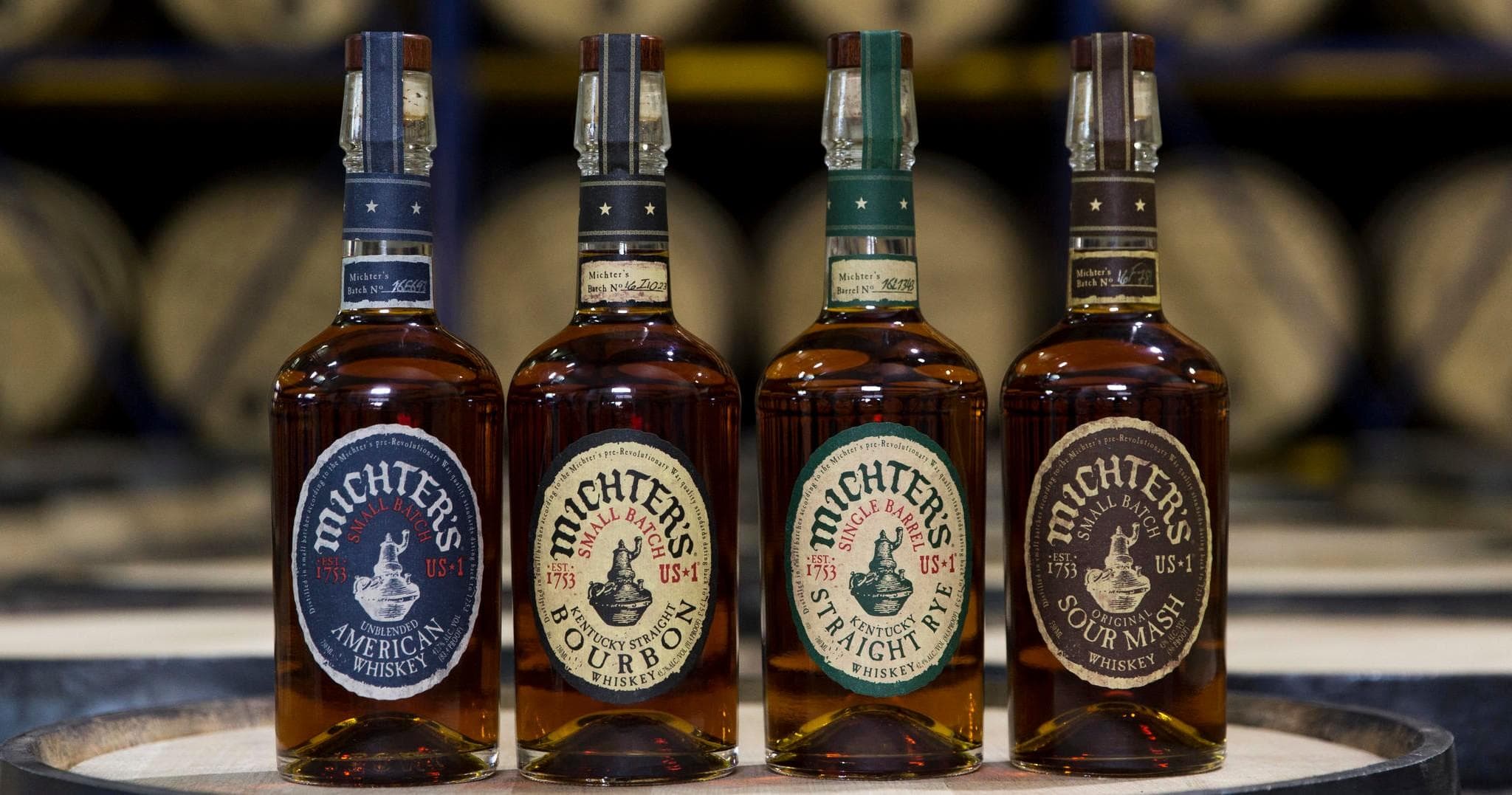 Four Michter's whiskey bottles on barrel in aging warehouse