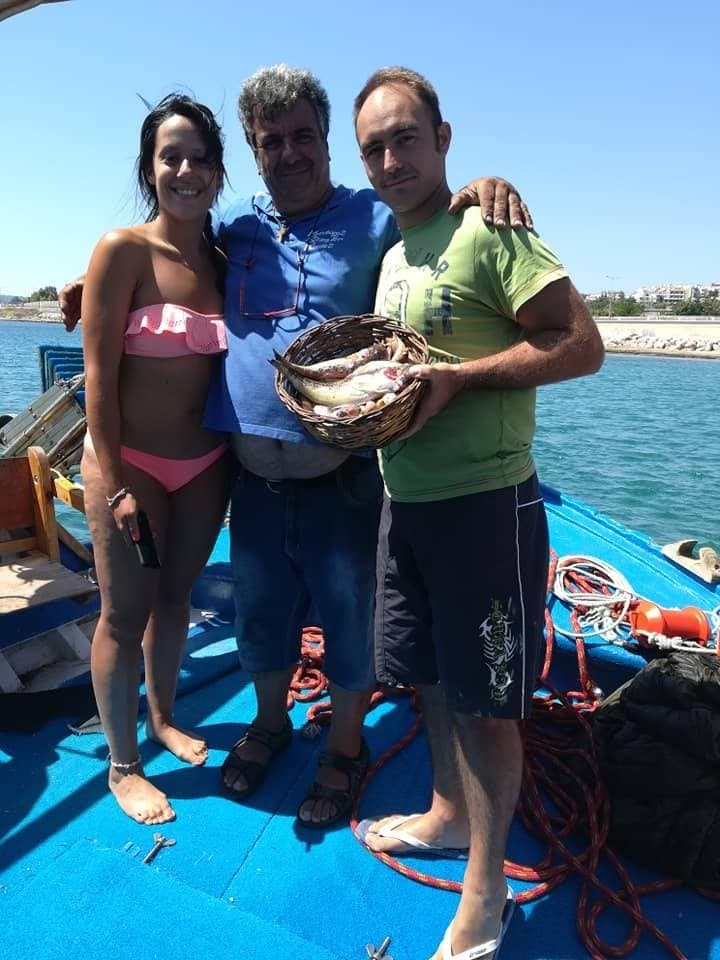 Three anglers posing with fresh catch aboard small fishing boat