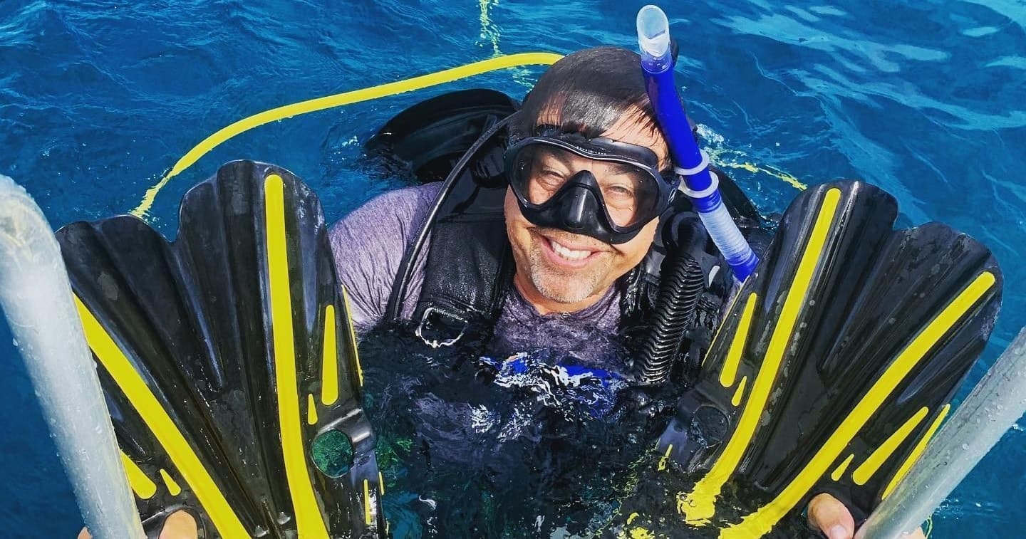 Smiling scuba diver surfacing with fins after open water dive