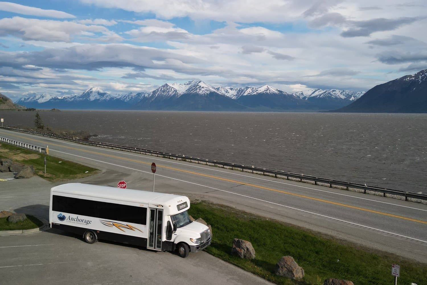 Shuttle bus parked on coastal highway with mountain views