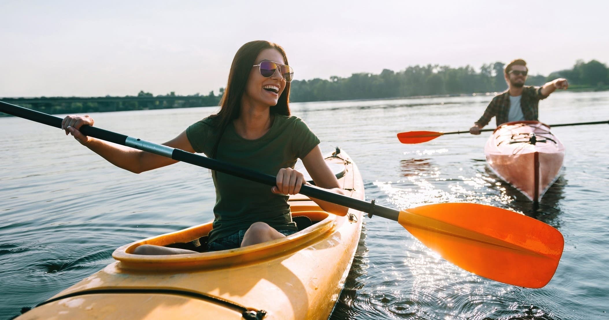 Smiling kayakers paddling on calm river near shoreline