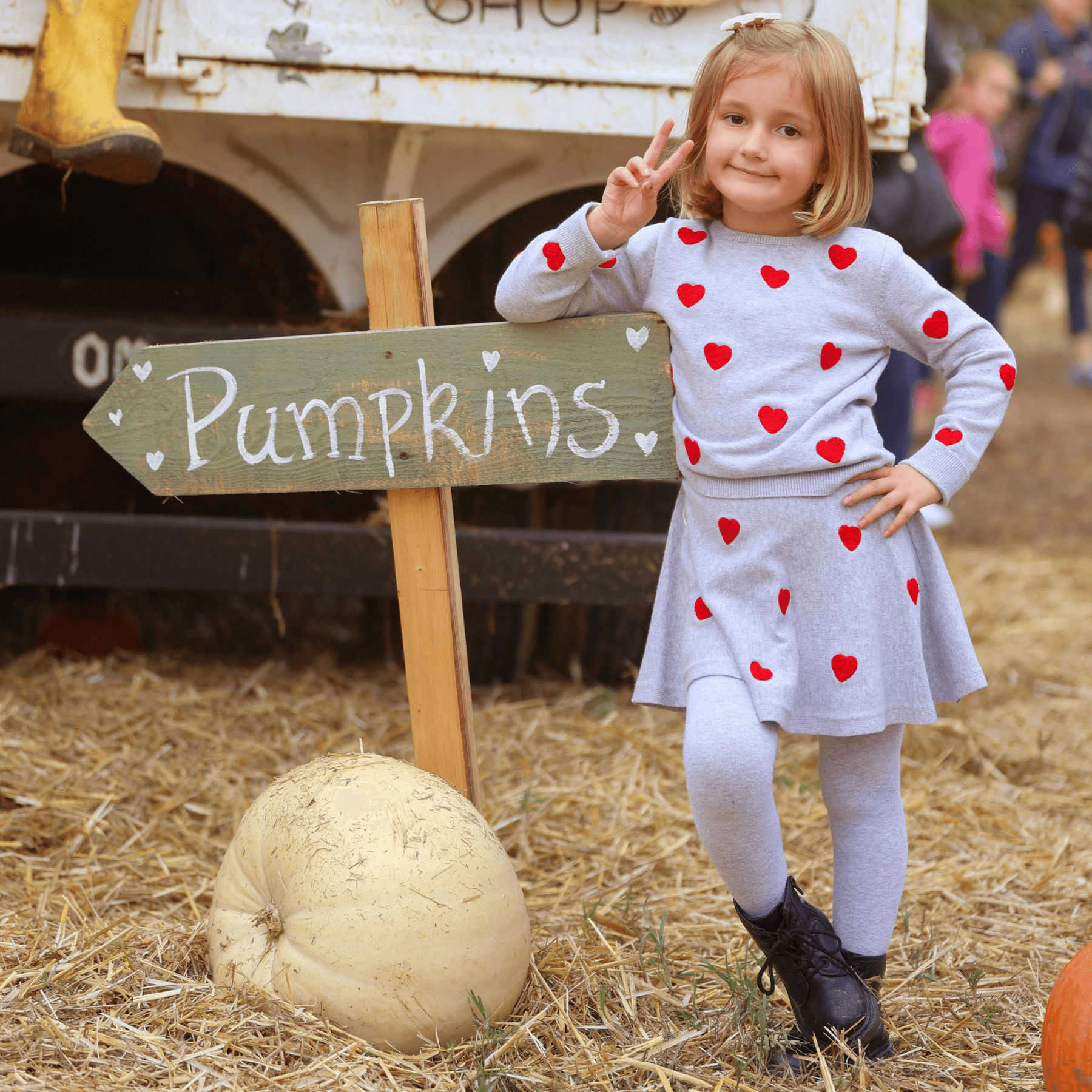 Child posing by pumpkins at a family pumpkin patch farm