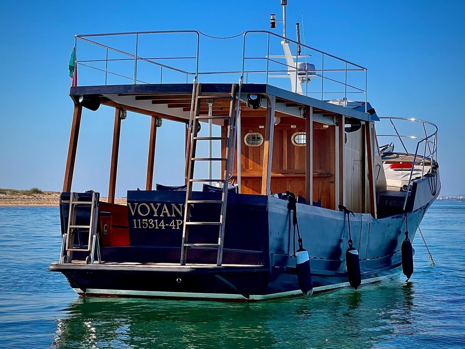 Stern of a charter boat moored in clear bay, onboard access view
