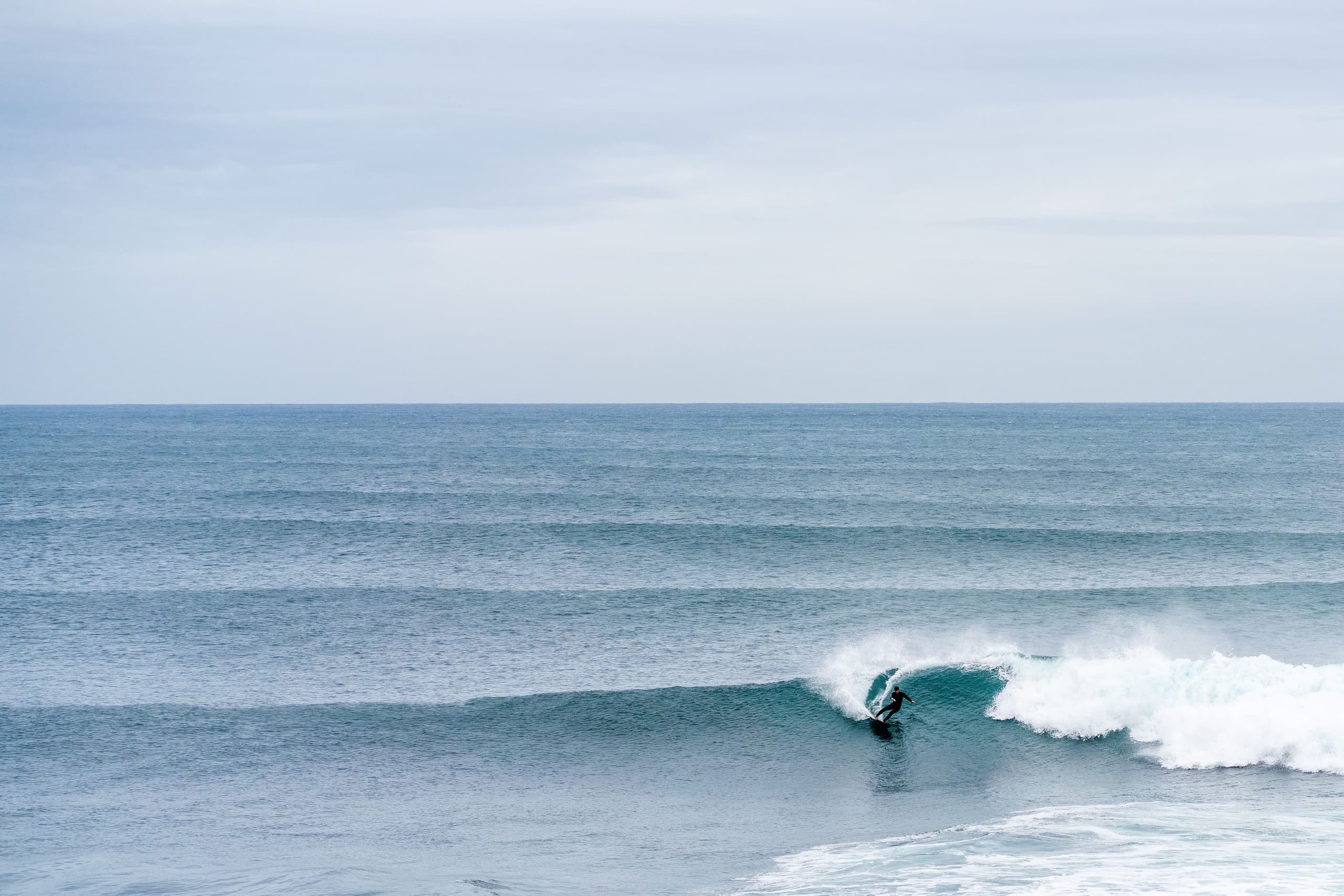 Surfer riding ocean wave on open sea, coastal surfing action