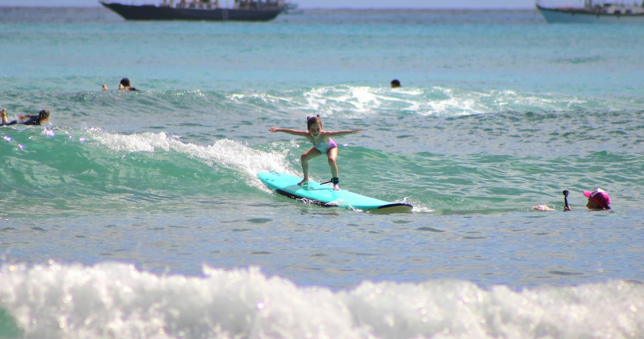 Beginner surfer riding small wave near shoreline, tropical ocean