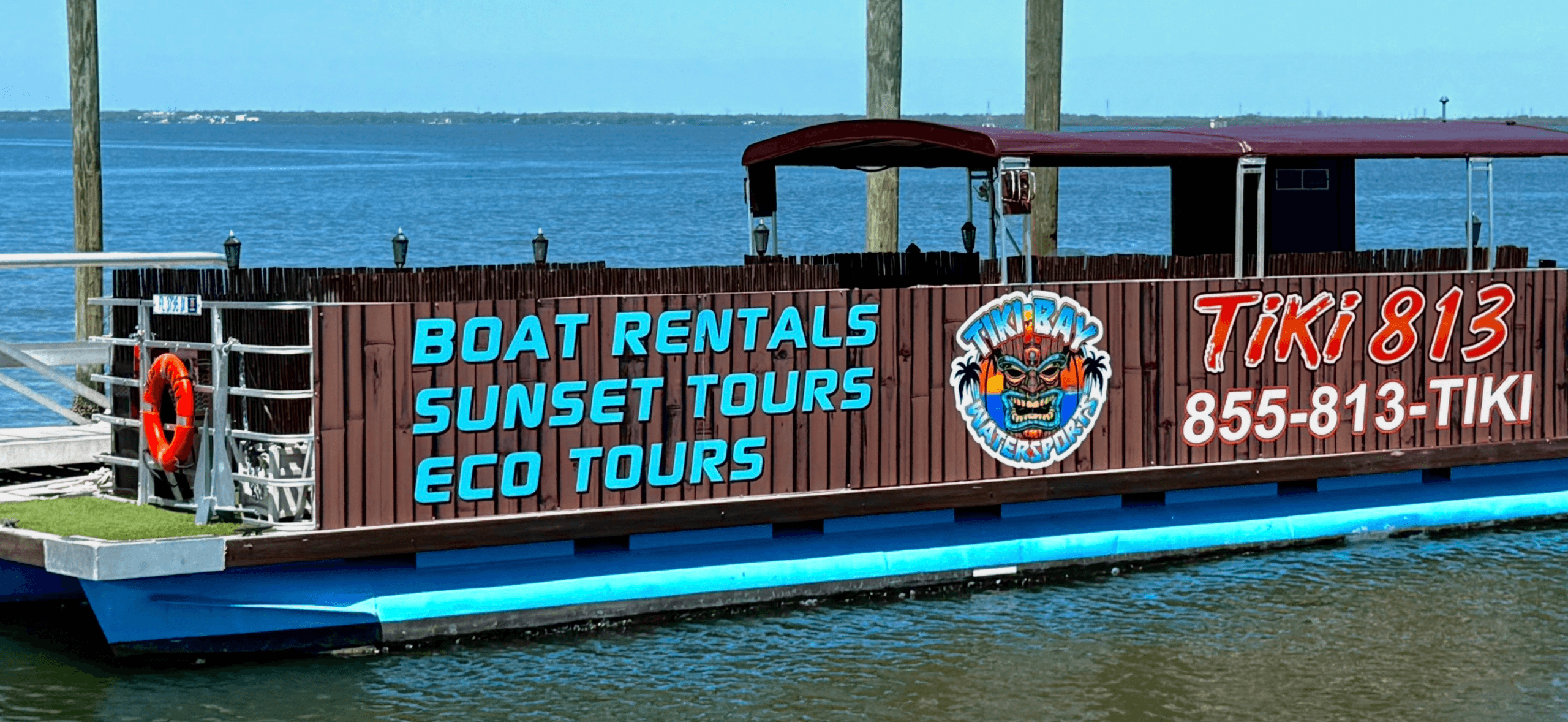 Tiki-themed rental boat docked advertising sunset tours on bay