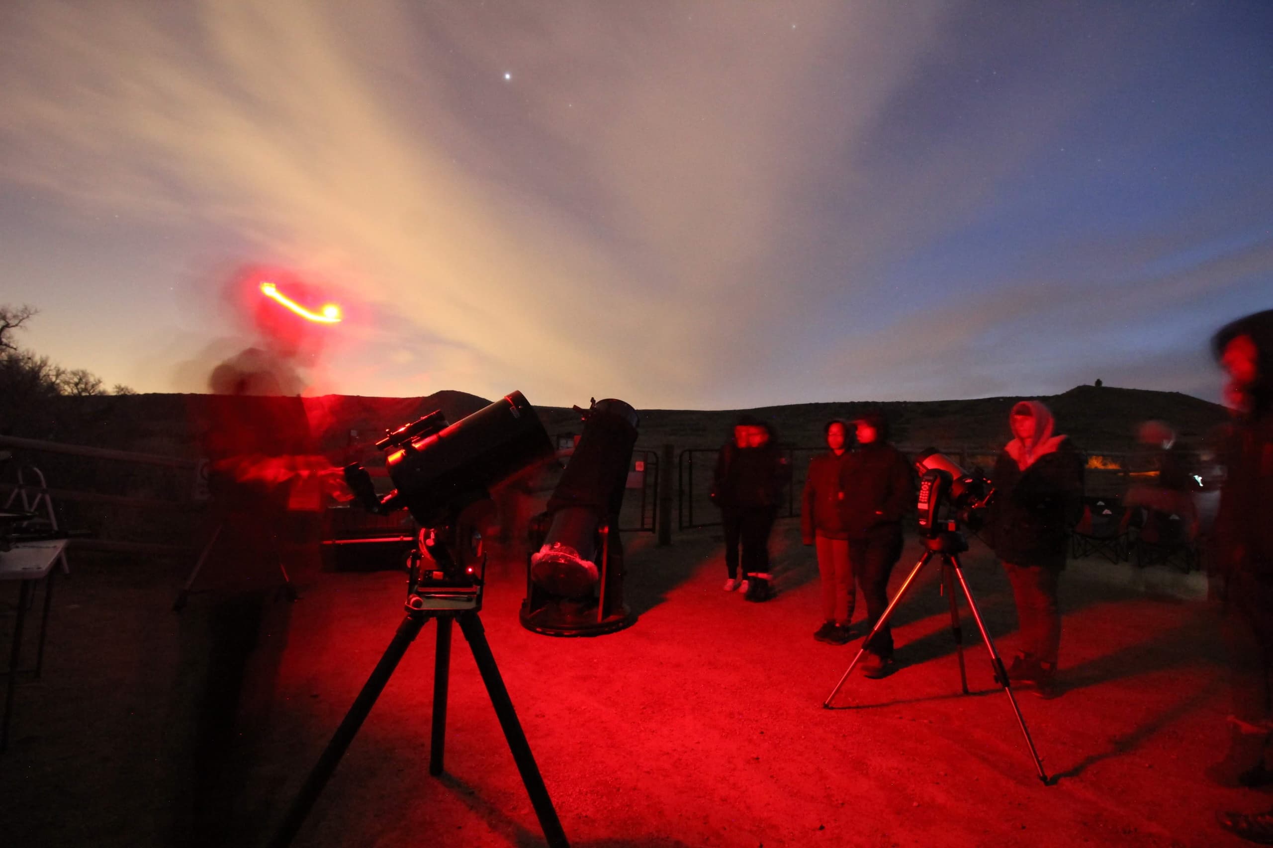 Group stargazing with telescopes and red lights at night