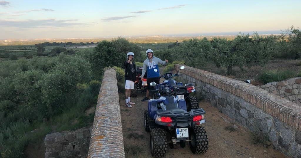 Quad biking on stone bridge at sunset across olive groves