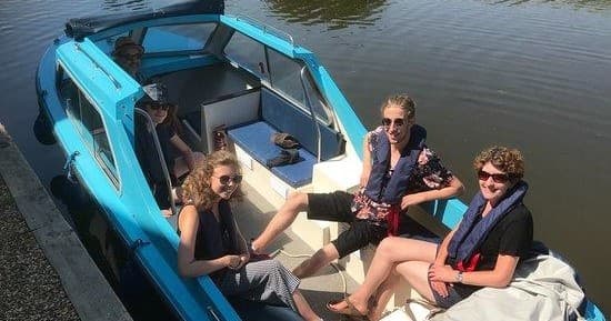 Friends relaxing aboard open boat on calm estuary cruise