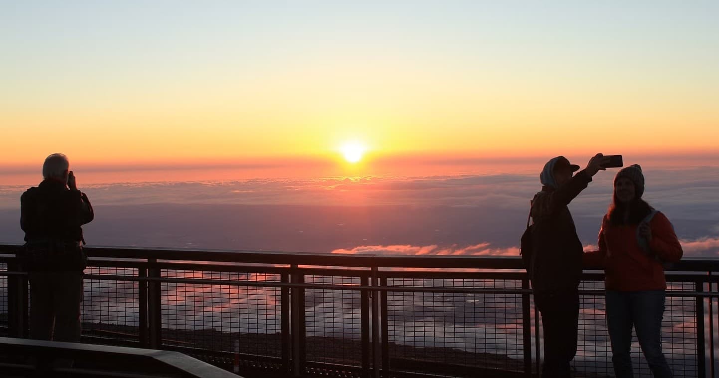 Sunrise viewpoint with silhouetted hikers on mountain observation deck