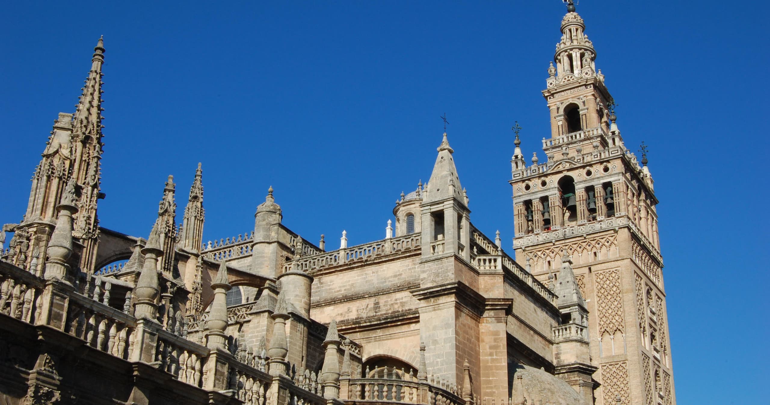 Seville Cathedral exterior and Giralda towers under blue sky