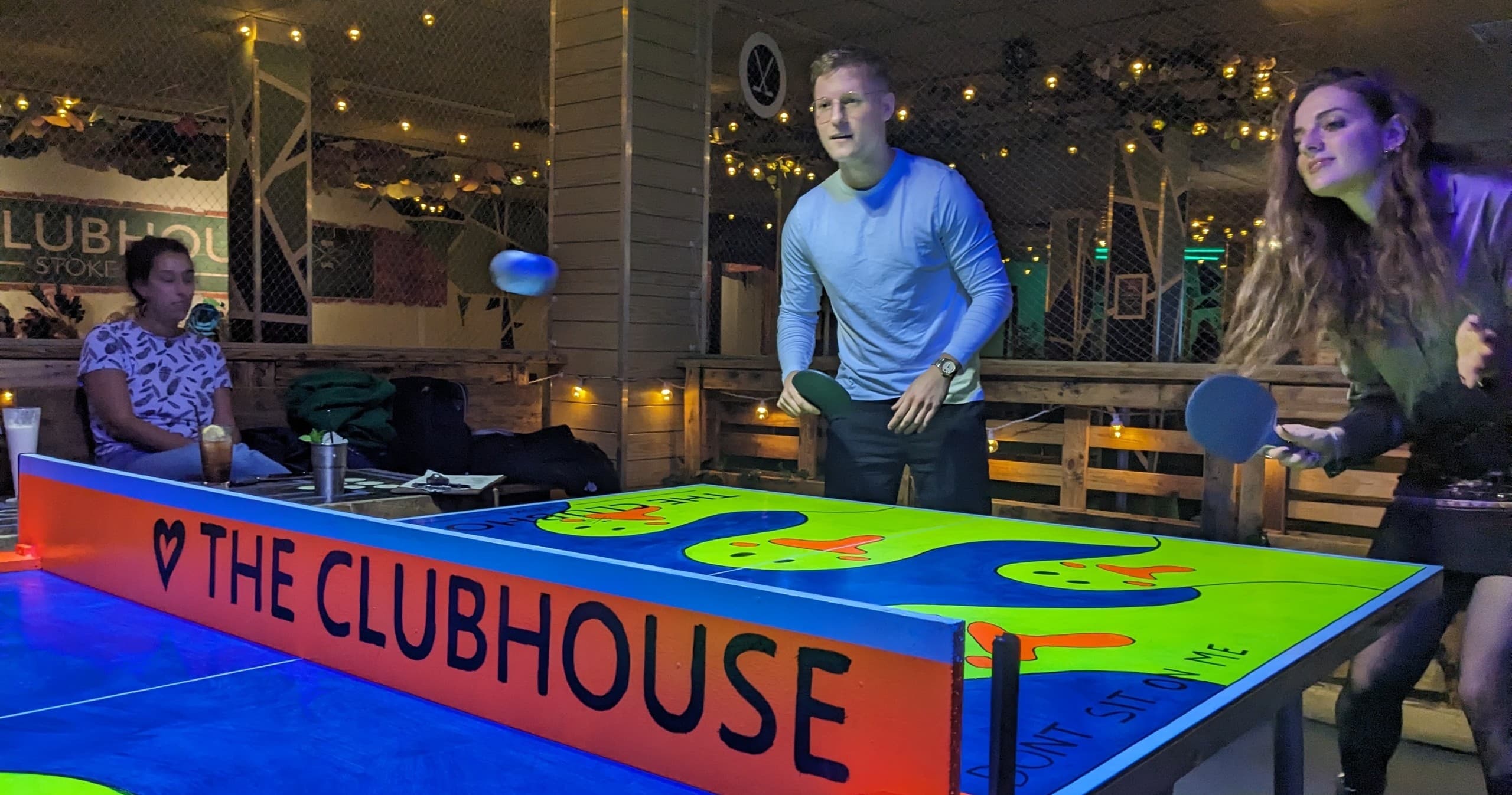 Friends playing air hockey at The Clubhouse indoor arcade