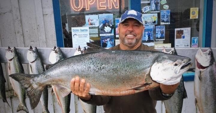 Fisherman displaying trophy salmon on dock after offshore trip
