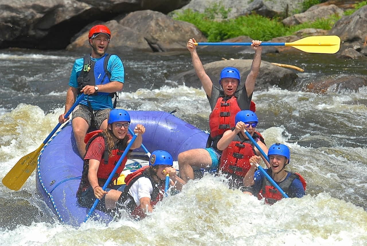 Guided whitewater rafting crew navigating turbulent river rapids