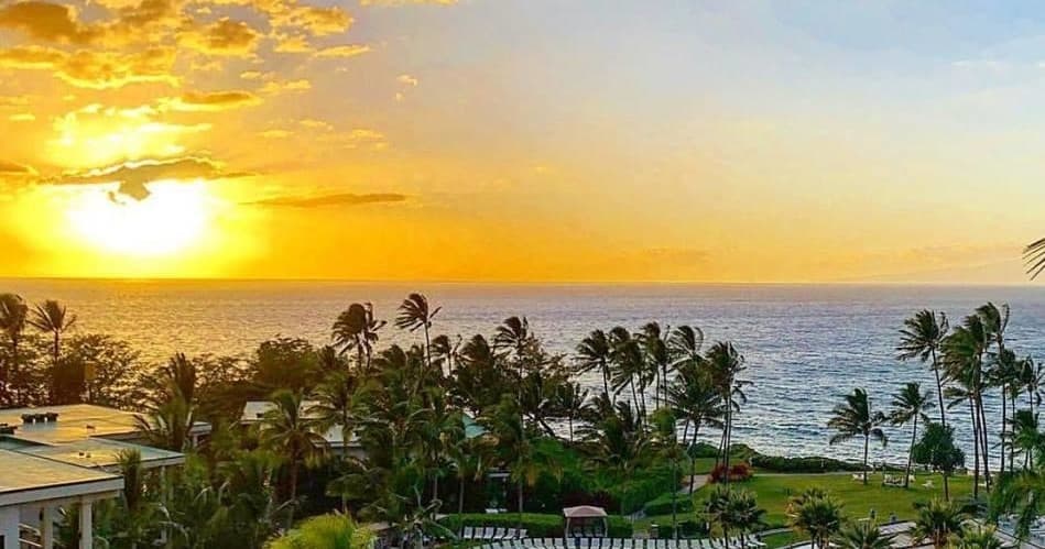 Sunset over Maui coastline with palm trees and ocean views
