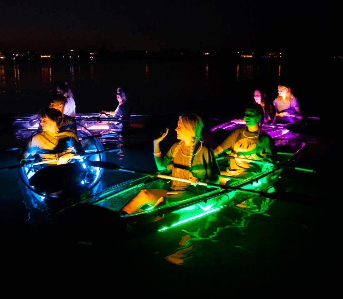 Night group paddling LED-lit clear kayaks on Key West bay
