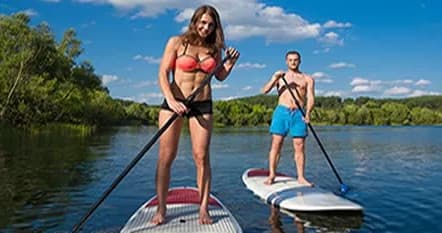 Stand-up paddleboarders cruising on scenic lake with tree-lined shore