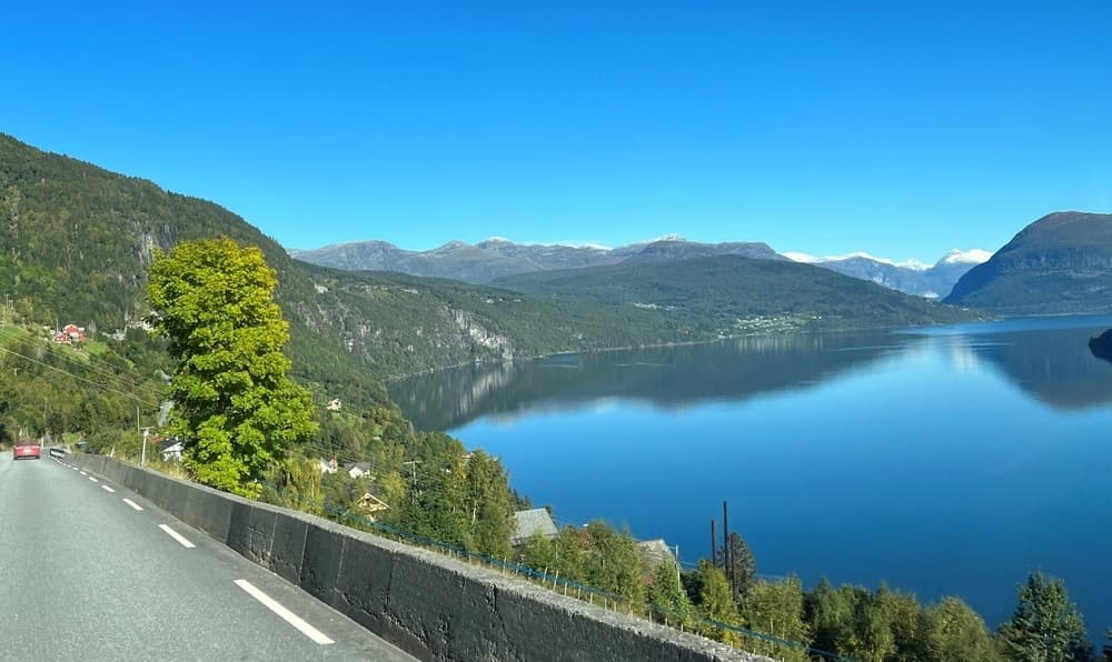 Scenic fjord road winding beside calm lake and mountains