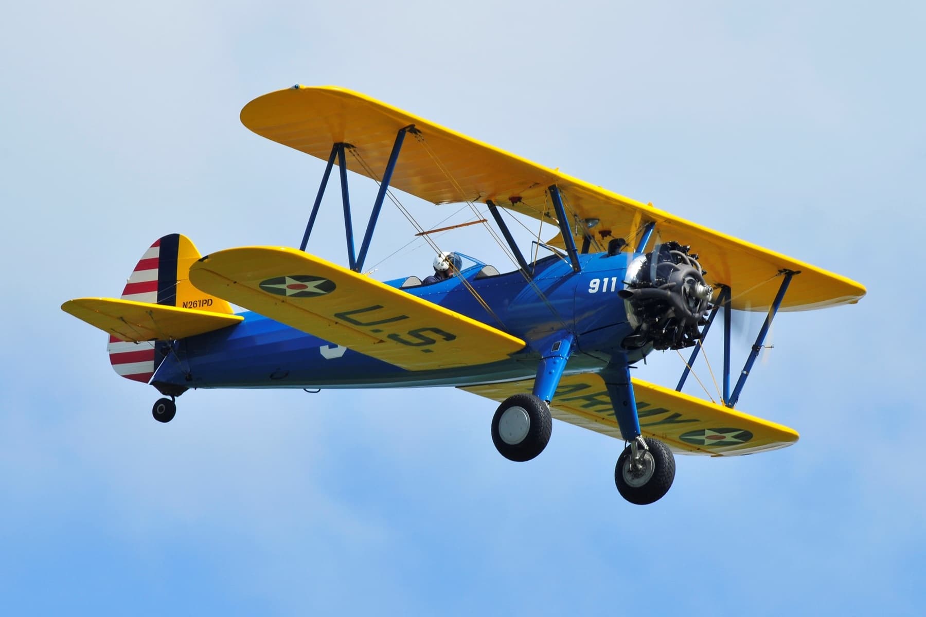 Yellow-and-blue biplane flying against clear blue sky