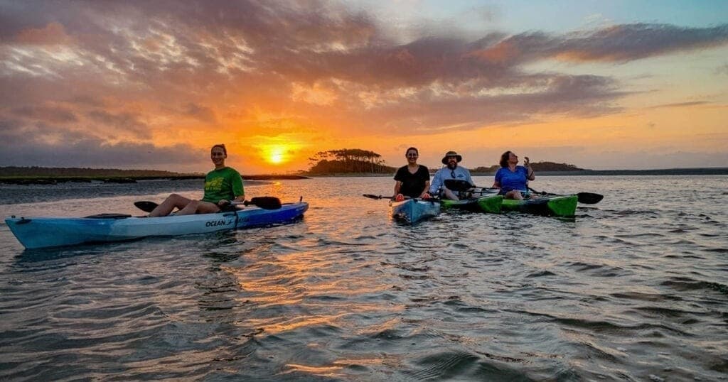 Group kayaking at sunset on coastal waters with paddling