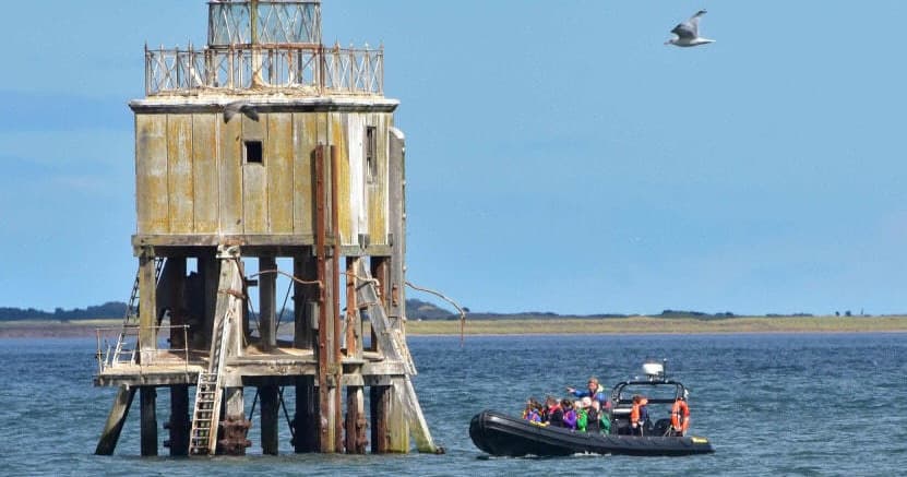 Historic sea tower with zodiac tour boat, offshore sightseeing