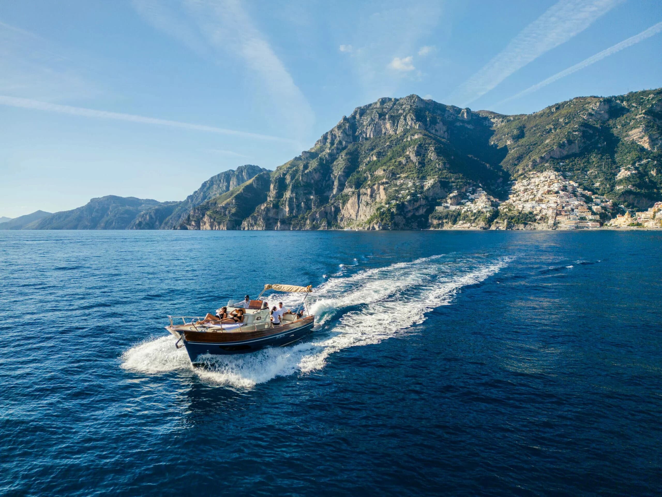Speedboat cruising along Amalfi coast, wake and coastal hills