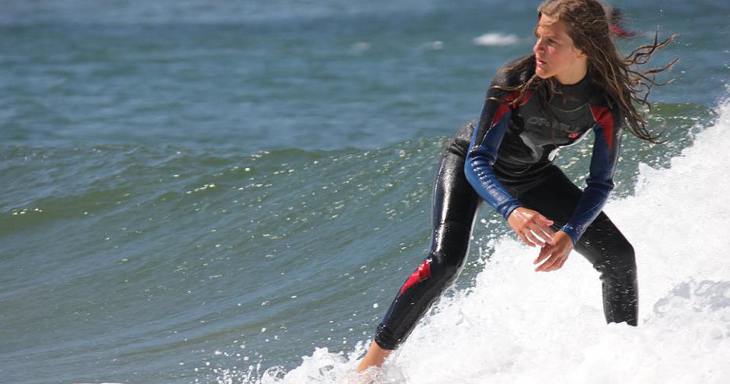 Surfer riding an ocean wave near coastline during daylight session