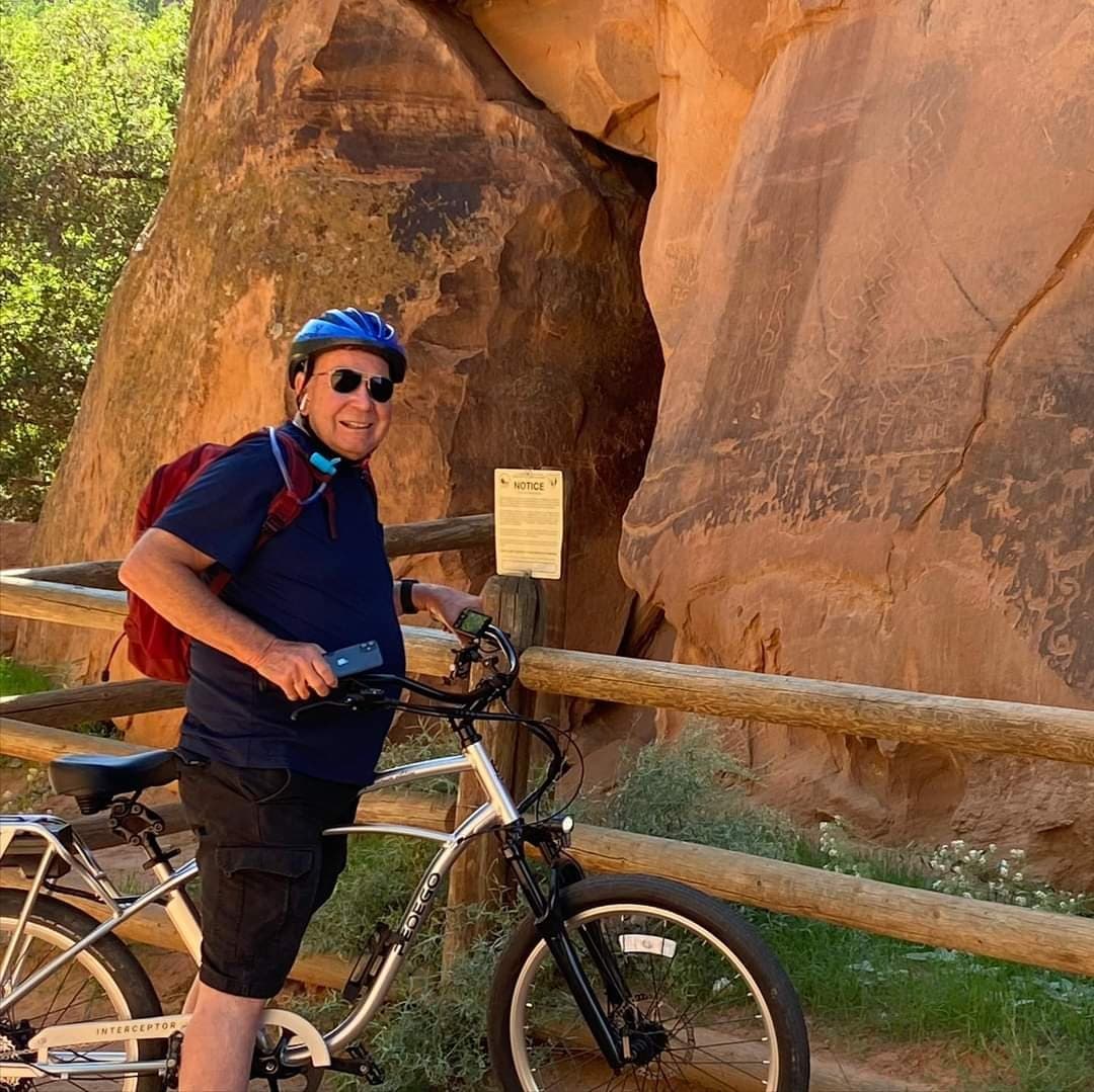 Cyclist posing by red rock canyon trail near sandstone arch