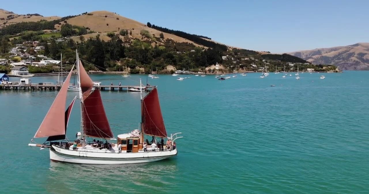 Sailing tour in Akaroa Harbour, New Zealand on red-sailed ketch
