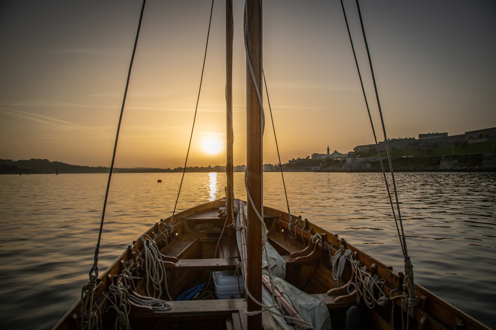 Sailboat bow at sunset on calm bay, coastal sailing cruise