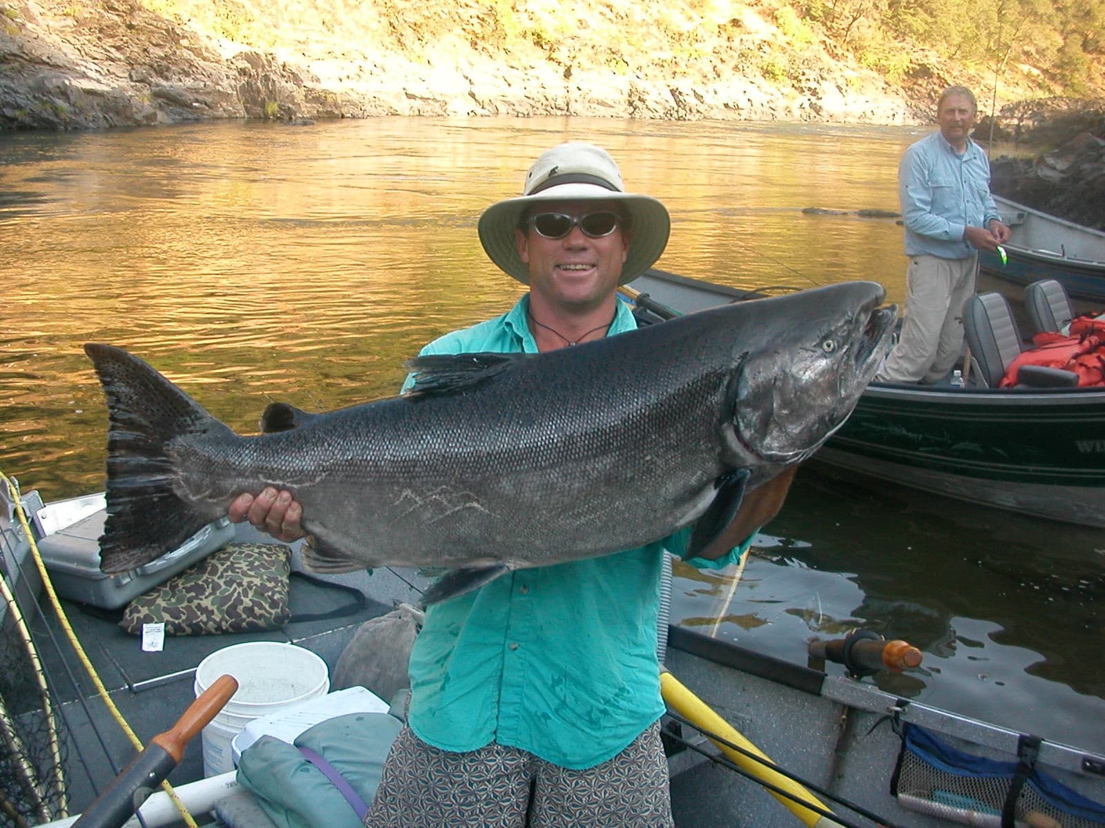 Angler holding large salmon on river boat at golden hour