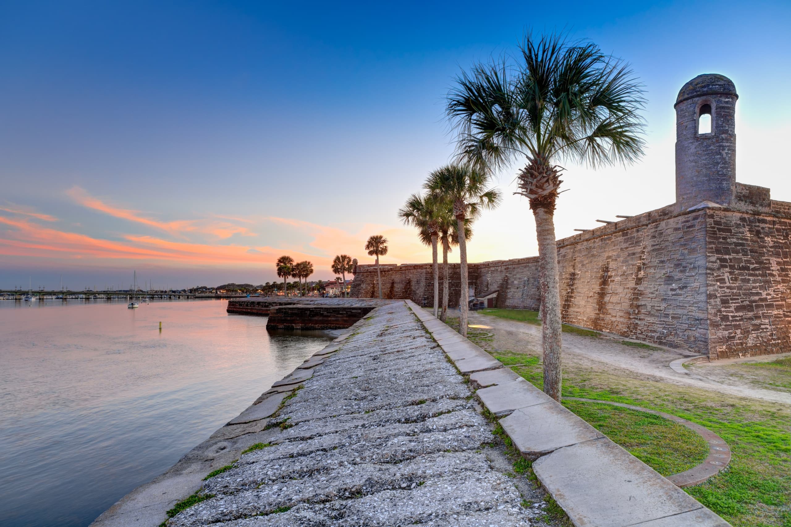Historic coastal fort walkway with palm trees at sunset in St. Augustine