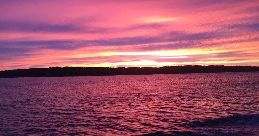 Vibrant purple-pink sunset over open lake with calm waves