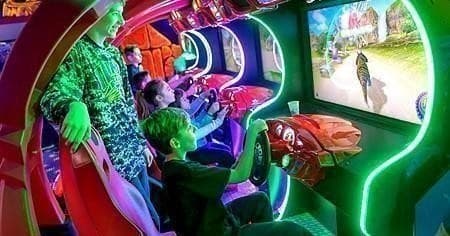 Kids playing arcade racing games in neon family fun center